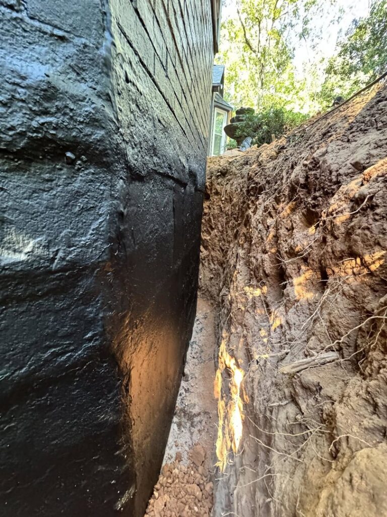 Exterior foundation waterproofing with a black coating and trenching by Carolina Pro Restoration LLC in Fort Mill, SC.