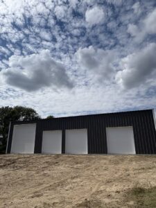 Four newly installed white panel garage doors on a commercial or industrial building by The Door Pros in Wichita, KS
