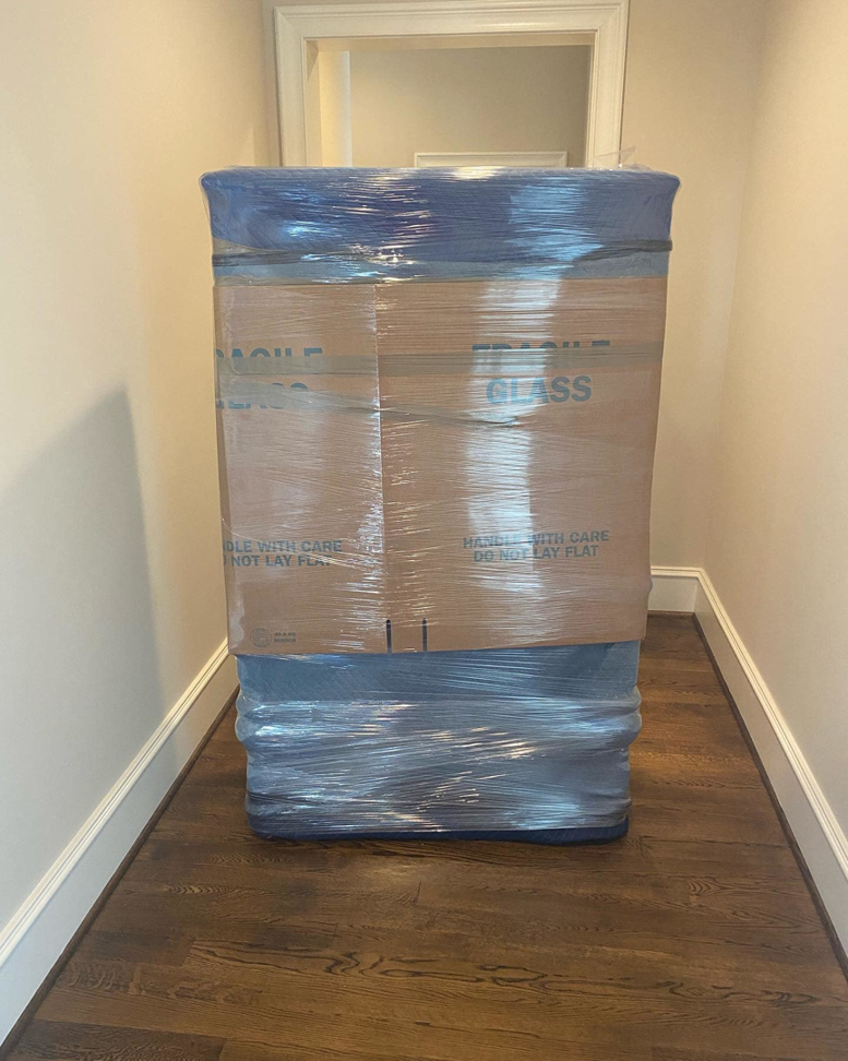 A fragile glass item securely wrapped in moving blankets and plastic, labeled for careful handling by CNZ Moving in Raleigh, NC.