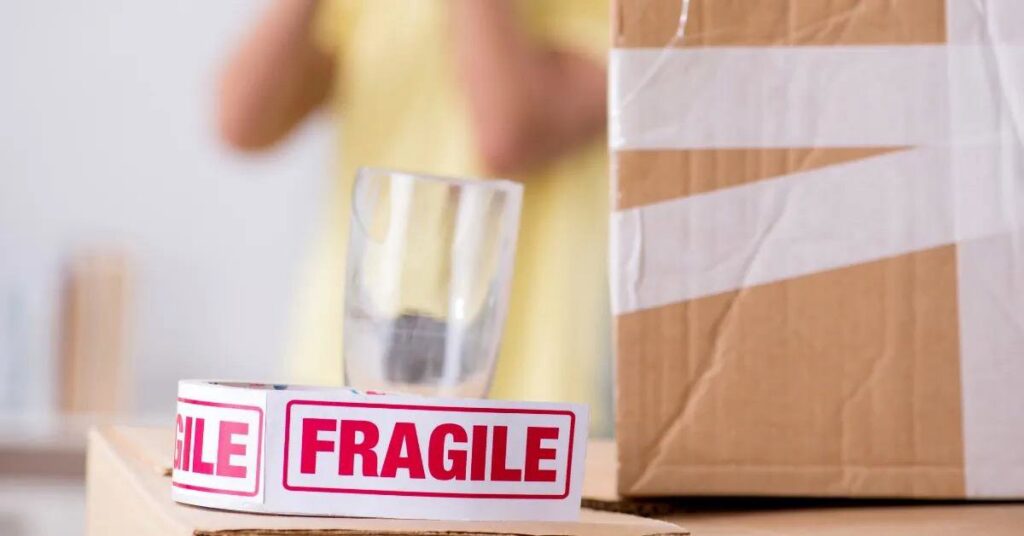 A close-up of a "FRAGILE" sticker on a moving box, showing careful packing by QuickTotes in Indianapolis, IN.