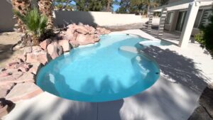 A beautiful freeform swimming pool with clear blue water and natural rock landscaping by Fix A Pool in Las Vegas, NV