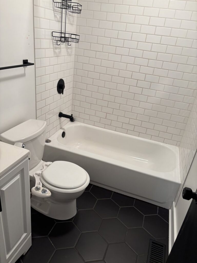 A freshly cleaned residential bathroom with a toilet, bathtub, and white subway tiles, by Uniquely Clean Professional Services in Kansas City, MO.