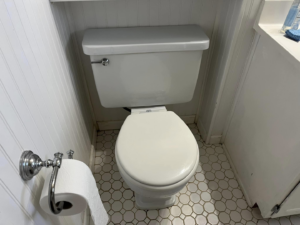 A freshly cleaned toilet with white wainscoting and hexagonal floor tiles by Shine Bright Cleaning Co. in Overland Park, KS.