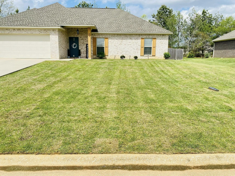 A freshly mowed front lawn with distinct stripes, showcasing professional lawn care by Big Buford's Lawn Care Service LLC in Tupelo, MS.
