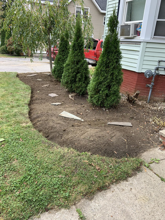 A freshly prepared garden bed with new plantings by Steele Lawns in Portland, ME, ready for landscaping.