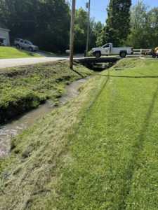 A freshly trimmed ditch with piles of cut grass, demonstrating professional cleanup by Ripley's Lawn Care, LLC in Charleston, WV.