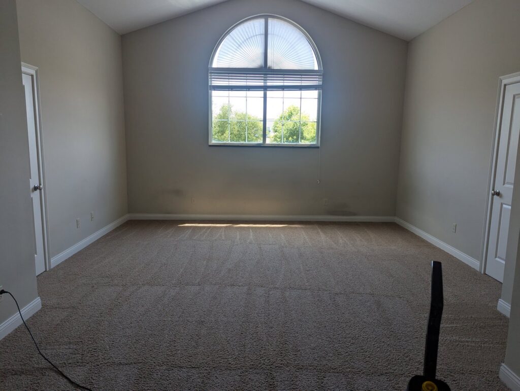 A freshly vacuumed bedroom with clean carpet and a large window, demonstrating house cleaning by Columbia Cleaners in Columbia, MO.