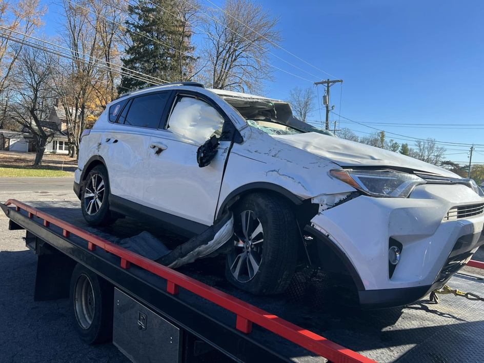 A front-damaged SUV with deployed airbags on a tow truck from Anytime towing services in Columbus, OH.