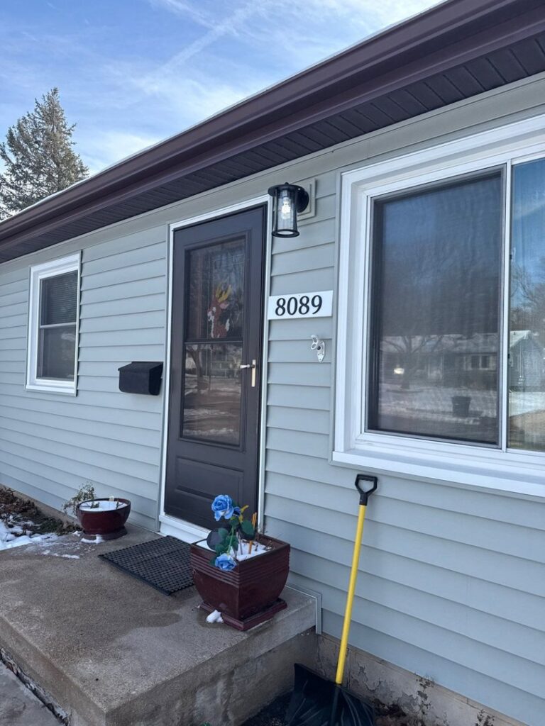 The front exterior of a house featuring newly installed light gray siding by Bishop Exteriors in Omaha, NE.