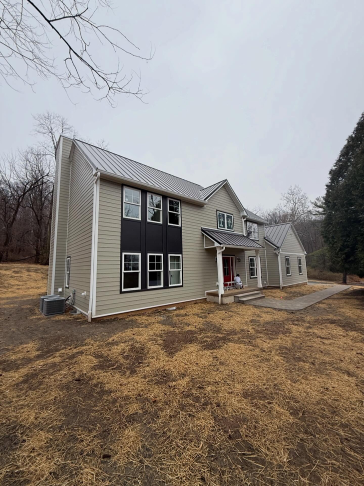 Front view of a home showcasing new light green siding with stylish dark accent panels installed by CRD Builders in Hamilton Township, NJ.