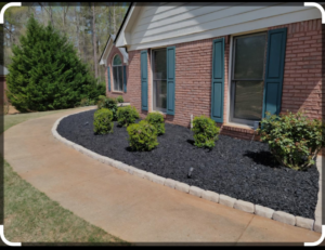 Front yard landscaping featuring black mulch, shrubs, and stone edging by Amazing Lawns & Lighting in Omaha, NE.
