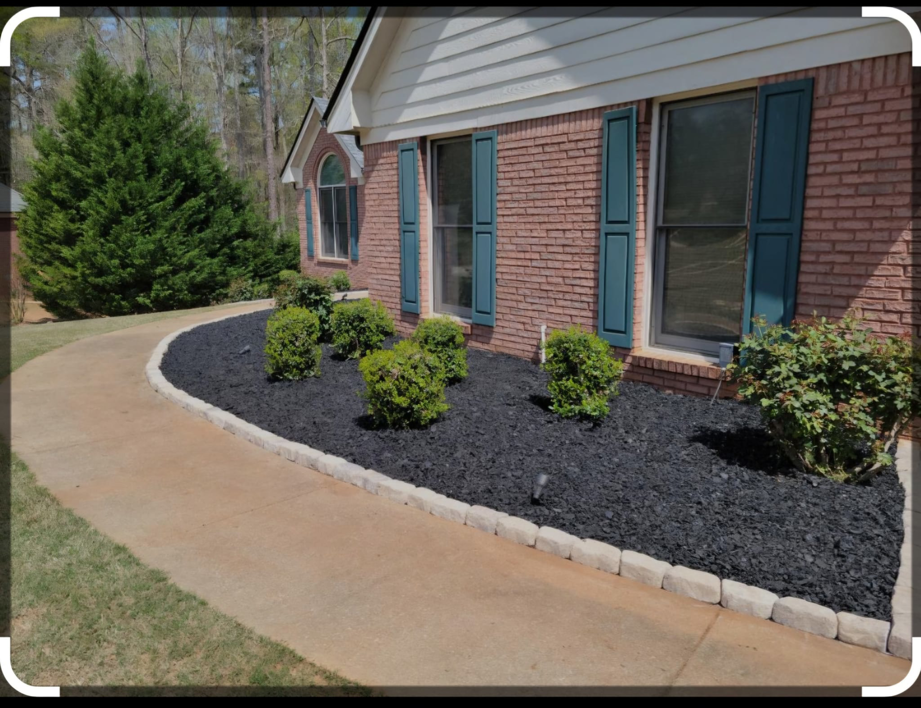 Front yard landscaping featuring black mulch, shrubs, and stone edging by Amazing Lawns & Lighting in Omaha, NE.