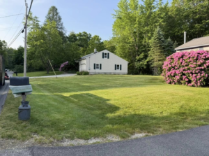 A freshly mowed front yard with clean lines, showcasing lawn care service by Merrily Landscaping LLC in Derry, NH.