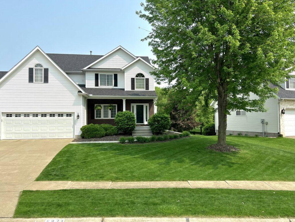 A beautifully manicured front yard with lush green grass and neat landscaping, maintained by Thompson Acres in Davenport, IA.