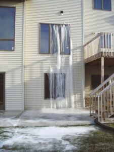 Building exterior showing severe frozen water leak damage with large icicles, handled by Specialized Cleaning & Restoration, Inc. in Bismarck, ND.