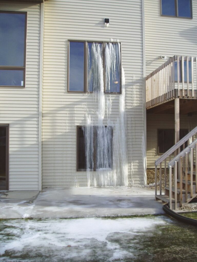 Building exterior showing severe frozen water leak damage with large icicles, handled by Specialized Cleaning & Restoration, Inc. in Bismarck, ND.