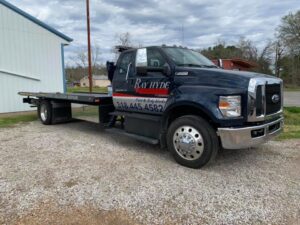 Full side view of a Ray Hyde Paint & Body Works flatbed tow truck in Alexandria, LA.