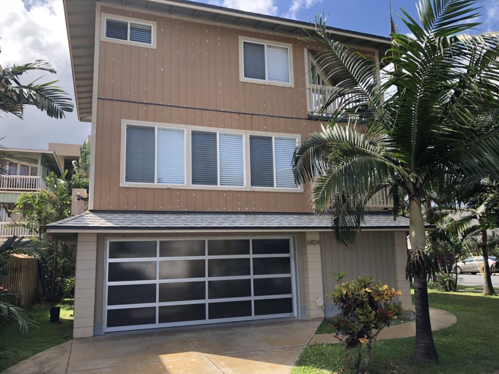 A modern full-view glass garage door installed on a house by Oahu Garage Doors in Waipahu, HI