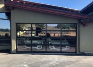 A full-view glass garage door installed by Overhead Door of Sierra Nevada, showcasing cars inside in Reno, NV.