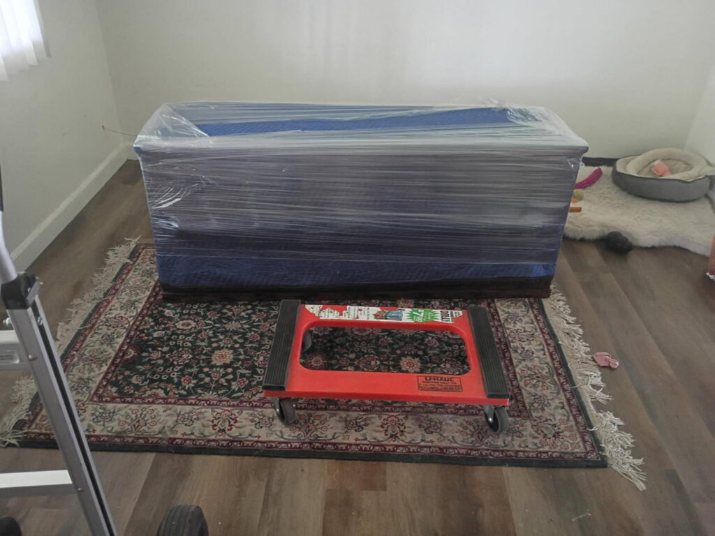 A piece of furniture carefully wrapped and ready for transport, with a moving dolly nearby, by Az Student Movers in Scottsdale, AZ