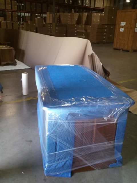 A piece of furniture wrapped in blue moving blankets and plastic wrap by Ang Moving Co in Dallas, TX