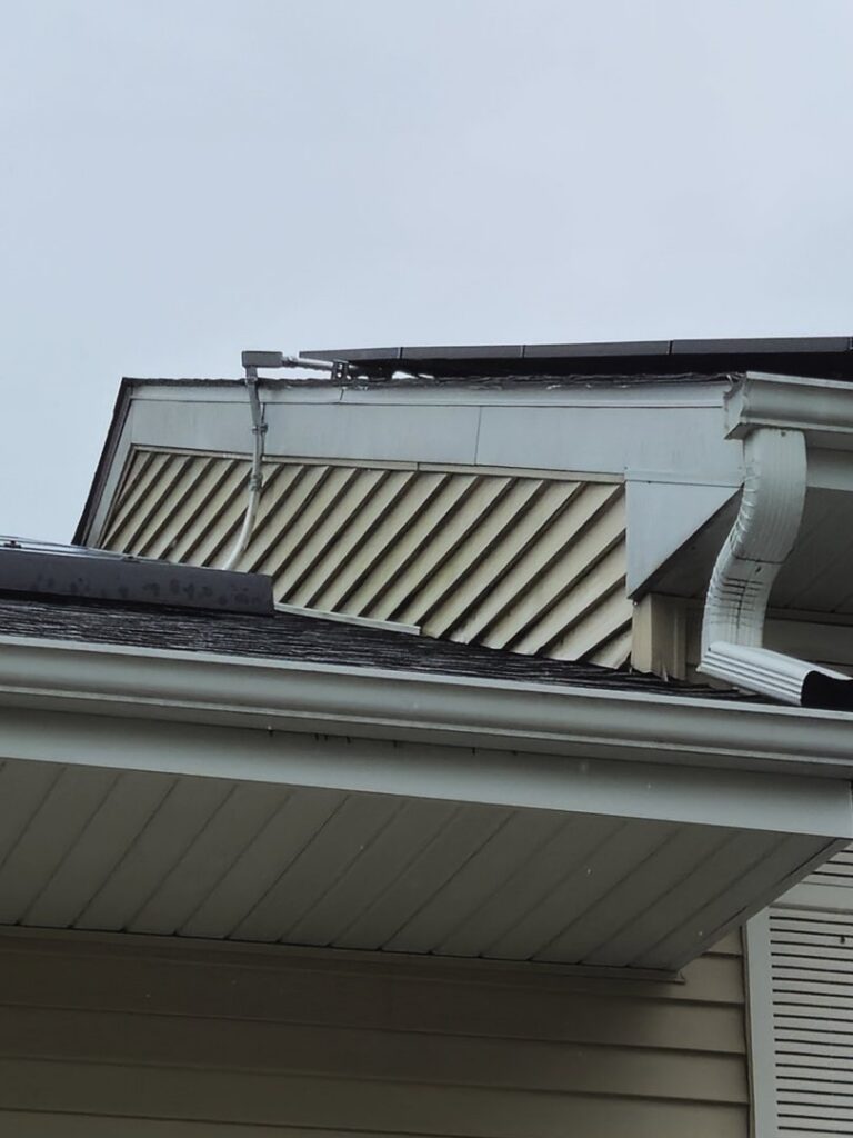 A close-up view of a house's gable vent, siding, and newly installed gutter by A&D Exteriors in Naperville, IL.