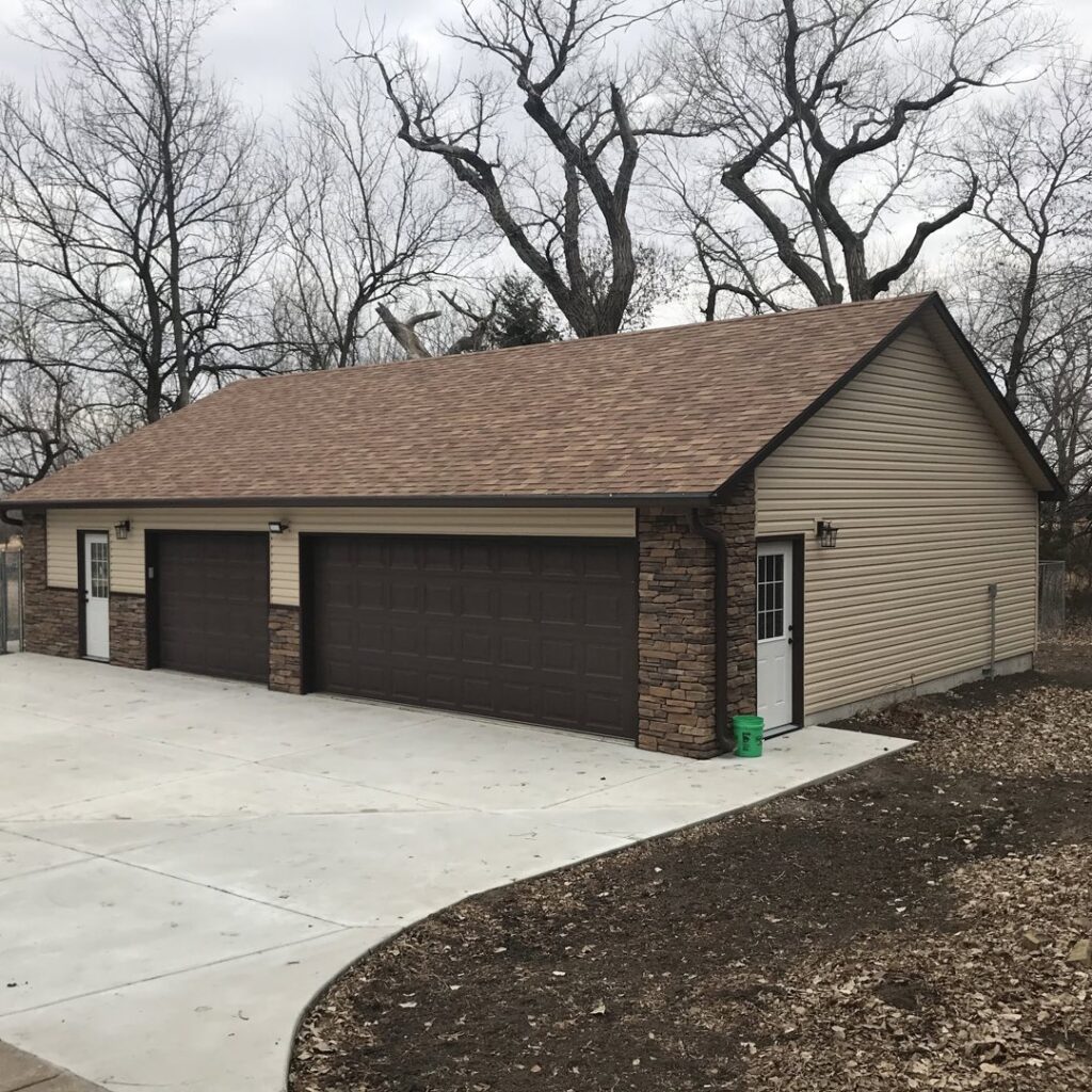 Newly built garage featuring beige horizontal siding and decorative stone accents by Southwestern Remodeling in Wichita, KS
