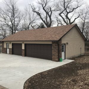 Newly built garage featuring beige horizontal siding and decorative stone accents by Southwestern Remodeling in Wichita, KS