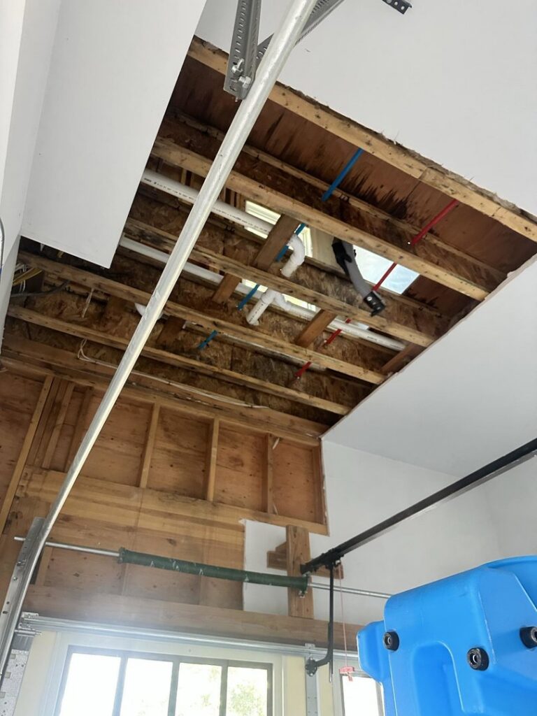 A garage ceiling with exposed joists and pipes, indicating water damage repair by RestoPros Hudson County in Jersey City, NJ.