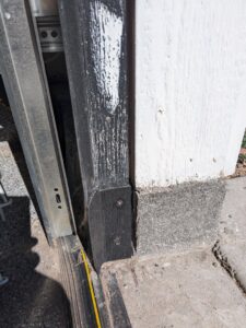 A close-up view of a garage door's bottom seal and track, indicating installation or repair work by Overhead Door Company of Santa Fe in Santa Fe, NM.