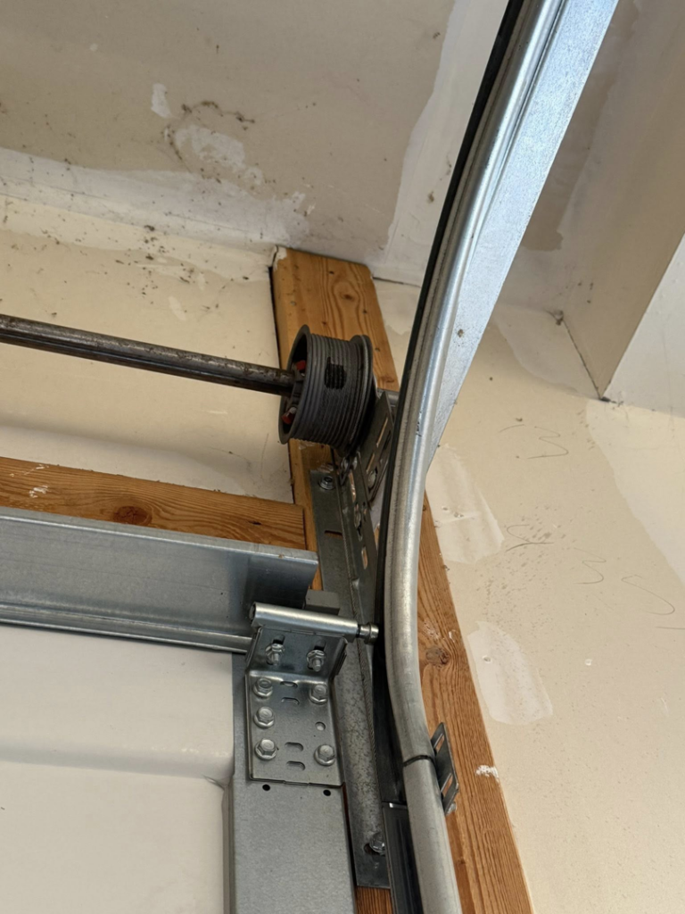 A detailed view of a garage door cable drum, track, and roller system by A-1 Garage Door Repair in Syracuse, UT.