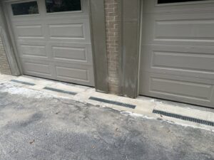 Newly installed drainage grates in front of garage doors to manage water runoff by HNO Waterproofing & Slab Lifting Pros in Concord, NC.
