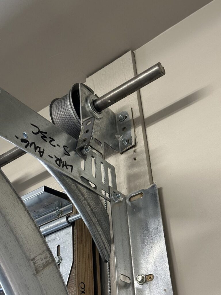 Close-up of garage door hardware components, including a spring and cable drum, serviced by Riverside Garage Doors in Kalispell, MT.