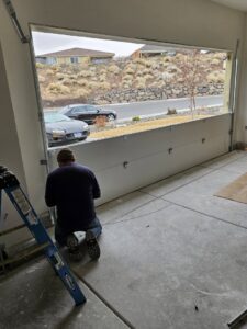 A garage door technician working on an installation, with the door partially open, for 775 Overhead Doors in Carson City, NV.