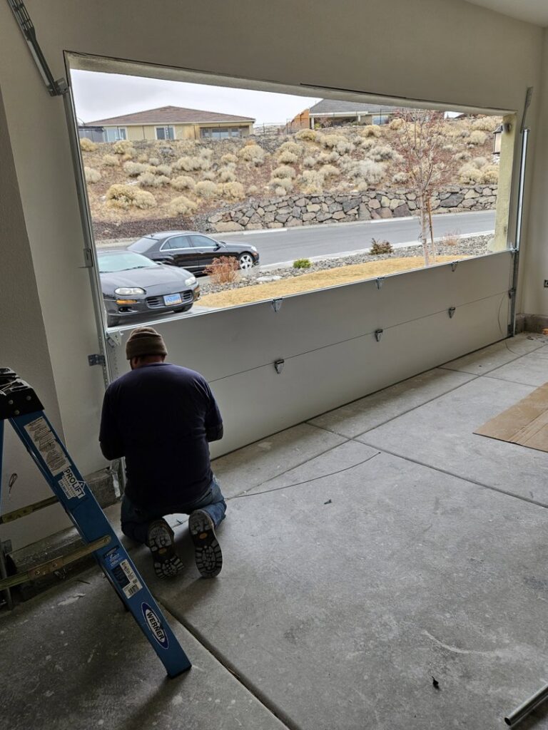 A garage door technician working on an installation, with the door partially open, for 775 Overhead Doors in Carson City, NV.