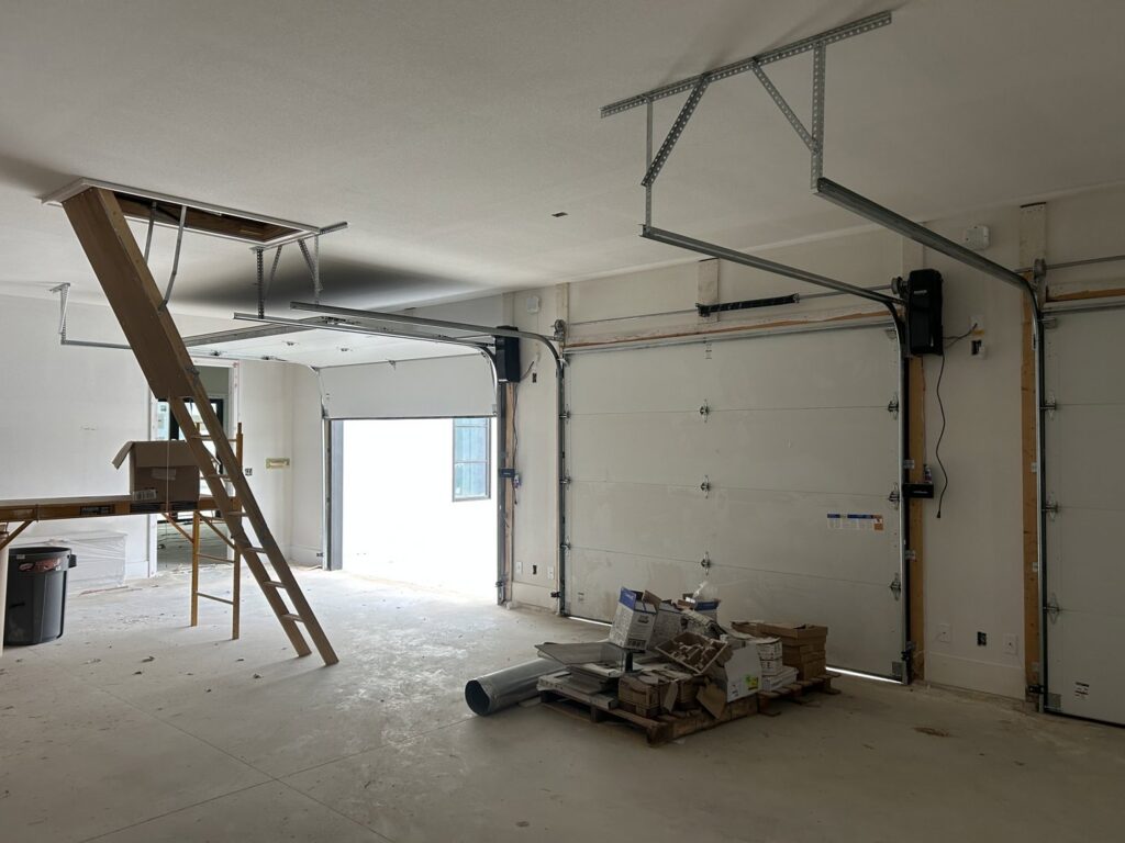 Garage door installation in progress, showing two white garage doors and tracks inside a new construction by Coney's Garage Doors in Conway, AR.