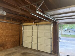 Interior view of a garage showing a newly installed white panel door and opener mechanism by The Door Pros in Wichita, KS