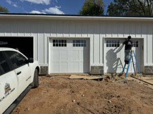 Technician installing a new garage door on a construction site for Garage Doors & More in Bentonville, AR
