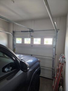 Interior view of a garage with a white sectional door and a ladder, indicating work by Oahu Garage Doors in Waipahu, HI