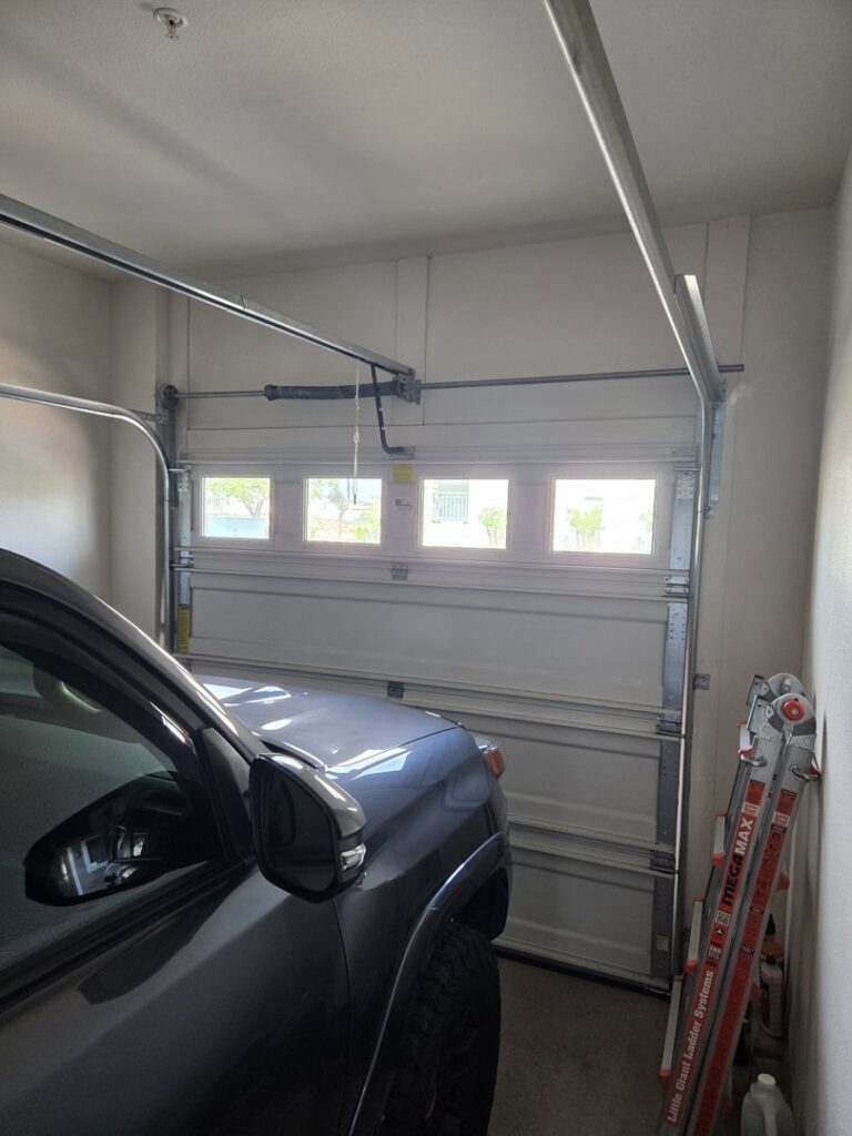 Interior view of a garage with a white sectional door and a ladder, indicating work by Oahu Garage Doors in Waipahu, HI