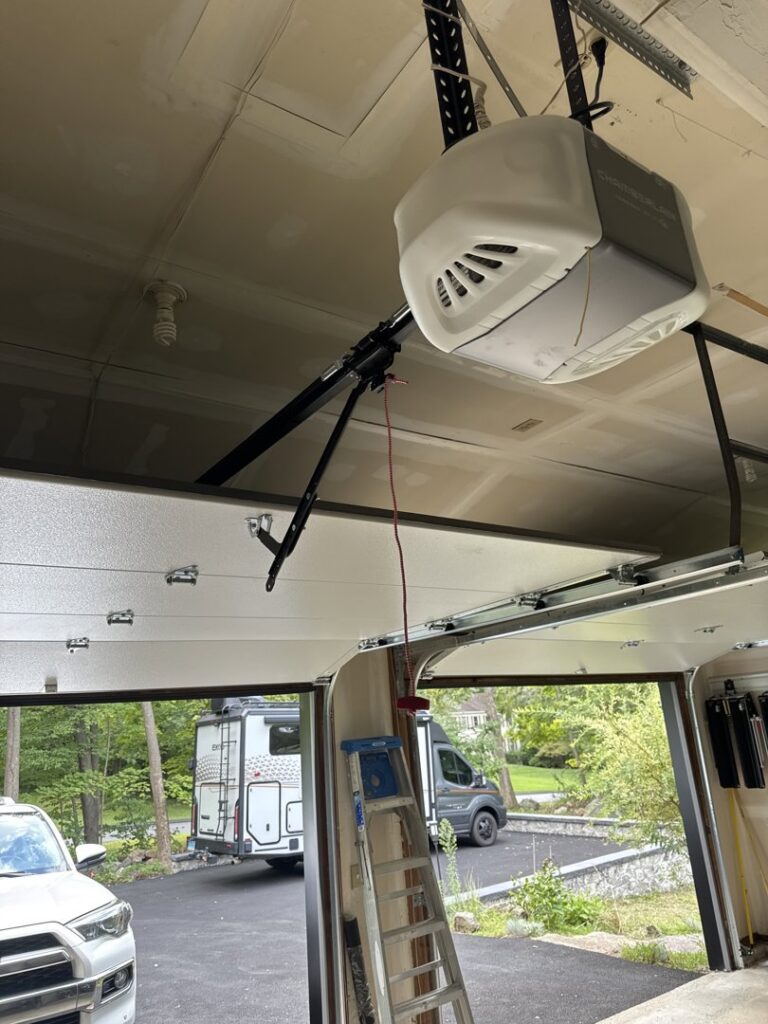 A garage door opener installation in progress with a ladder visible by Mascolo Overhead Doors & Maintenance in Brookfield, CT.