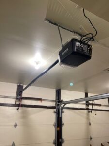 Interior view of a garage showing an installed garage door opener and white door by Up & Down Garage Doors in Bridgeport, CT.