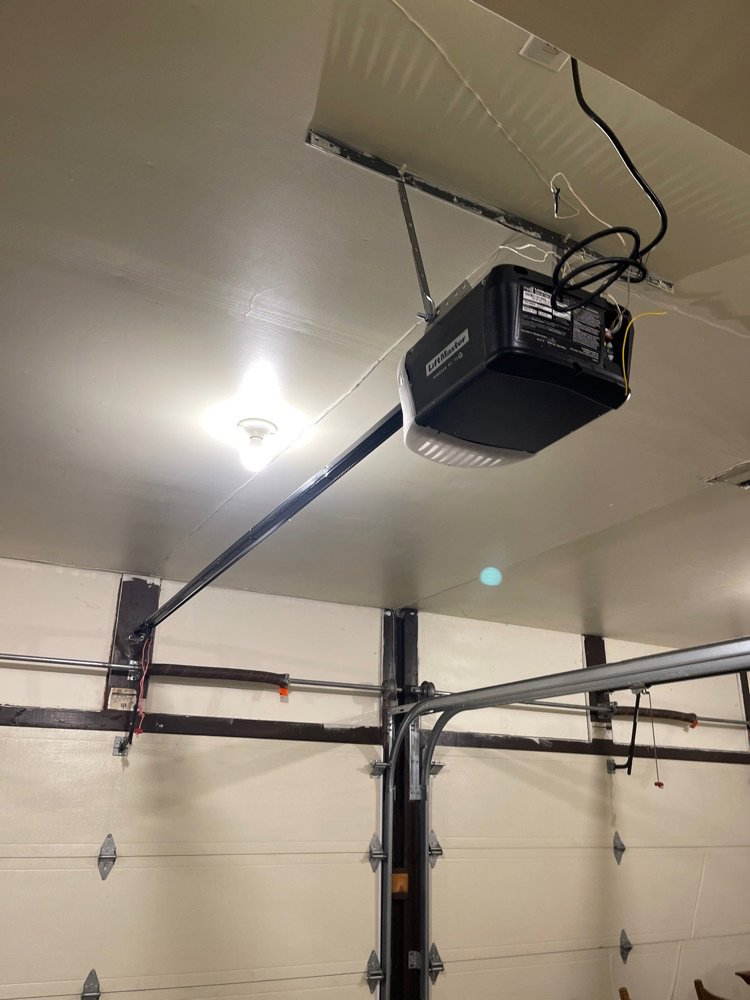 Interior view of a garage showing an installed garage door opener and white door by Up & Down Garage Doors in Bridgeport, CT.