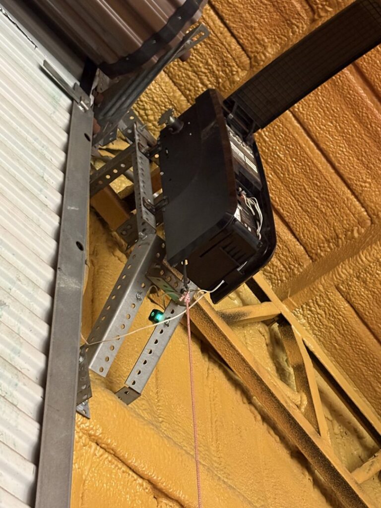A garage door opener unit and its mounting brackets being installed by Ultimate Garage Doors LLC in Olive Branch, MS.