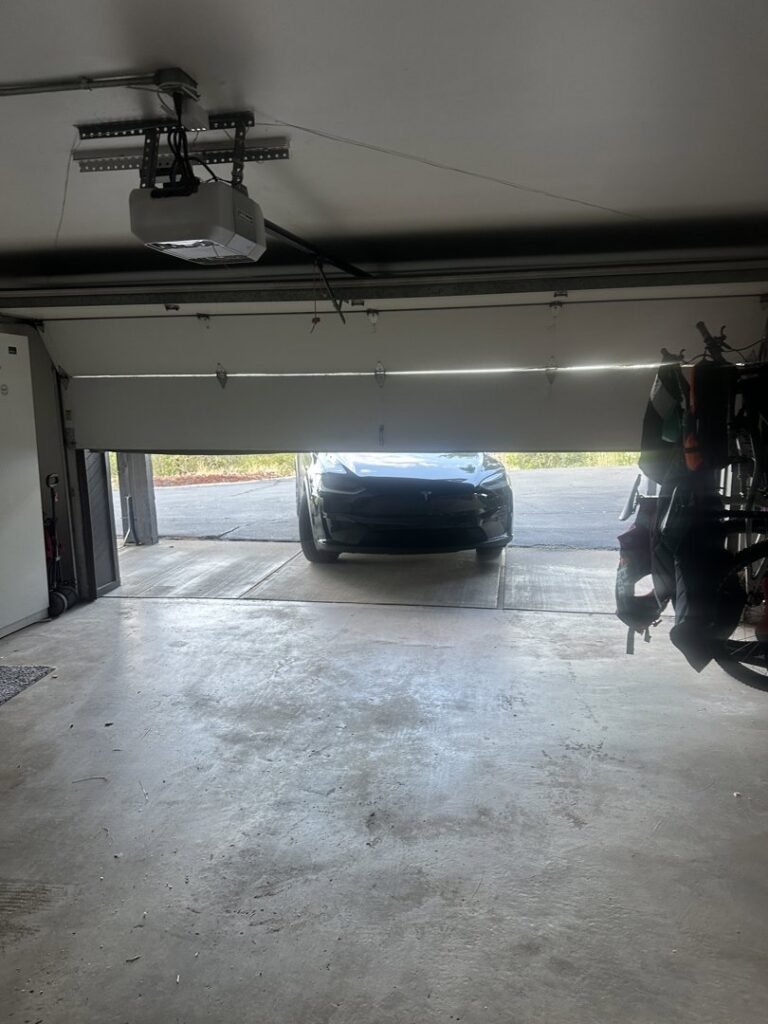 An inside view of a garage showing a partially open door and the opener mechanism, serviced by Windsor Door Sales Inc. in Ogden, UT.