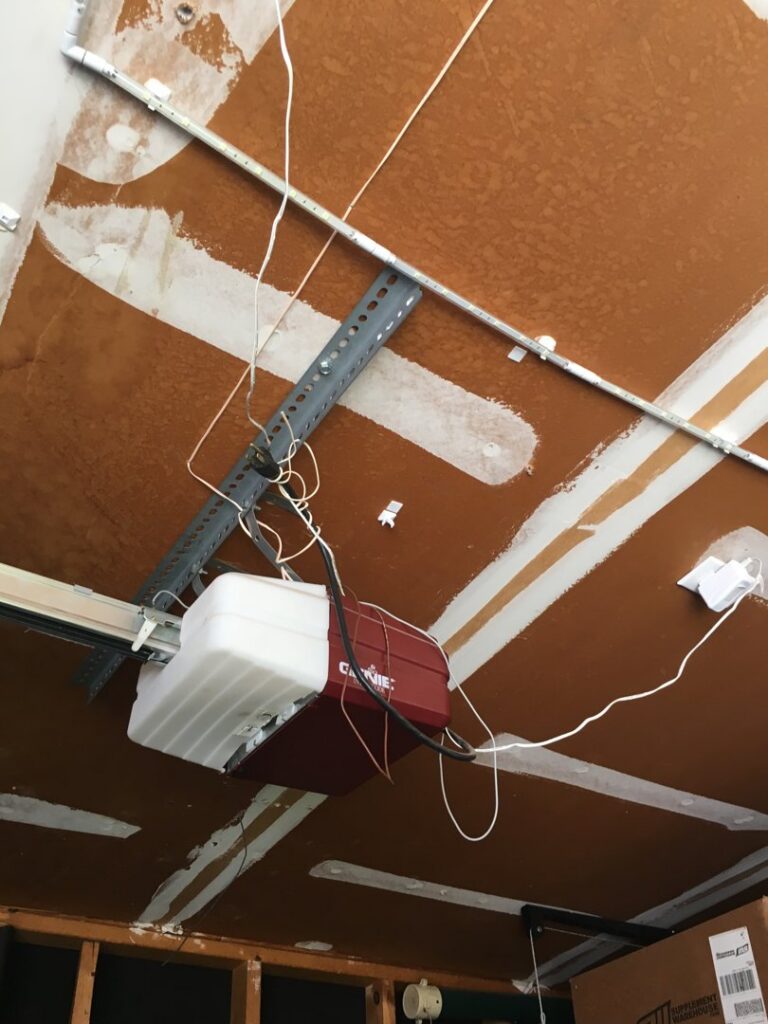 A garage door opener motor unit with power connection, installed by Overhead Door Company of Albuquerque in Albuquerque, NM.
