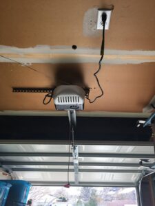 A garage door opener motor unit and rail system installed on a garage ceiling by Overhead Door Company of Albuquerque in Albuquerque, NM.
