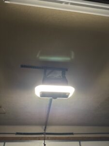 An installed garage door opener unit with its light on, showcasing work by Overhead Door Company of Salt Lake in Sandy, UT.