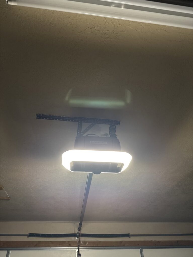 An installed garage door opener unit with its light on, showcasing work by Overhead Door Company of Salt Lake in Sandy, UT.