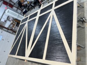 A garage door panel with decorative trim being assembled in a workshop by ABC Garage Doors KC in Kansas City, KS.